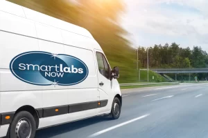 A white van with the Smart Labs Now logo speeds down the highway.