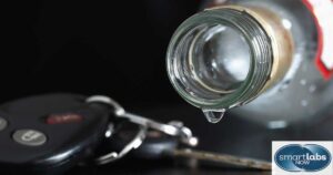 A car key next to an empty alcohol bottle.